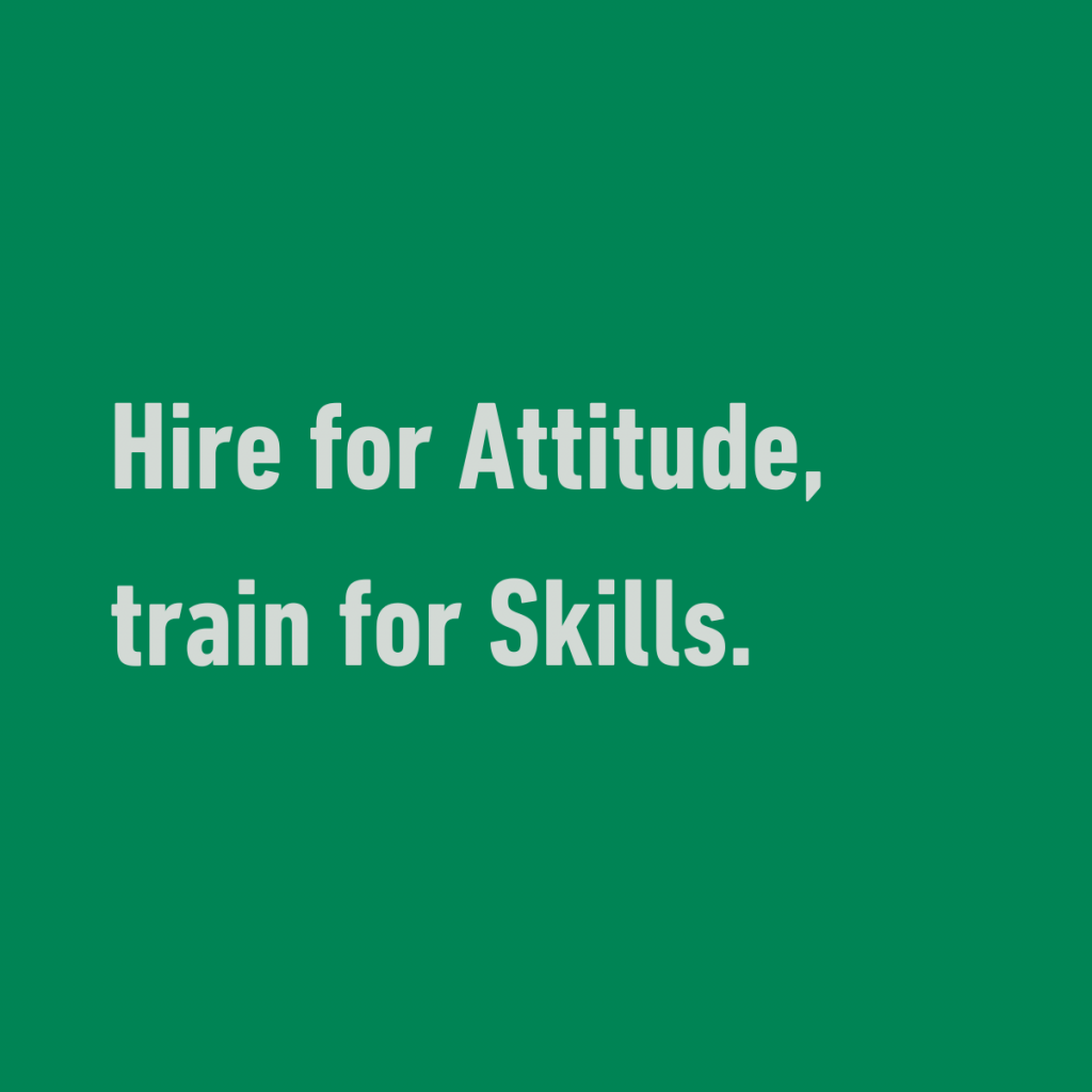 Grüne Fläche mit der Aufschrift "Hire for Attitude, train for Skills"