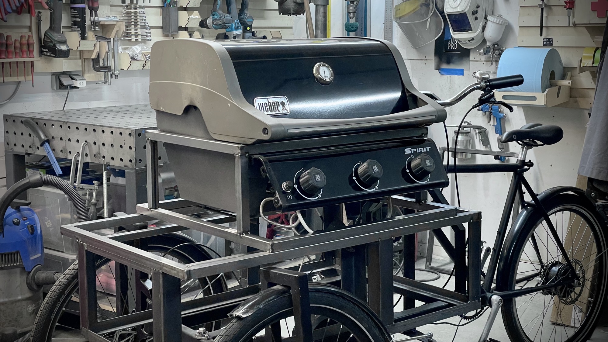 Weber-Grill im geschweißten Rahmen, daneben das umgebaute Rad